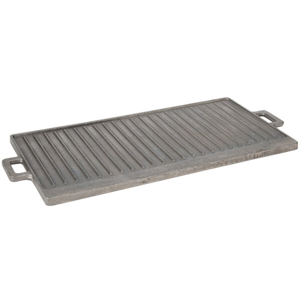 A FMP rectangular cast iron griddle and grill pan with handles on a concrete surface.