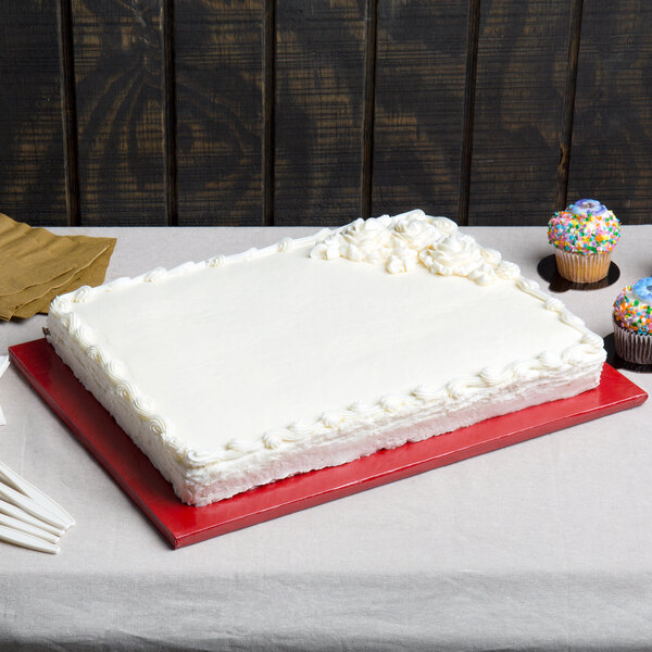 A white cake with frosting on a red Enjay cake board on a table.