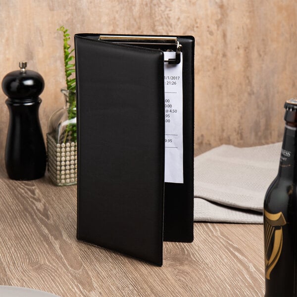 A black foam padded server book with a clip holding a white paper.