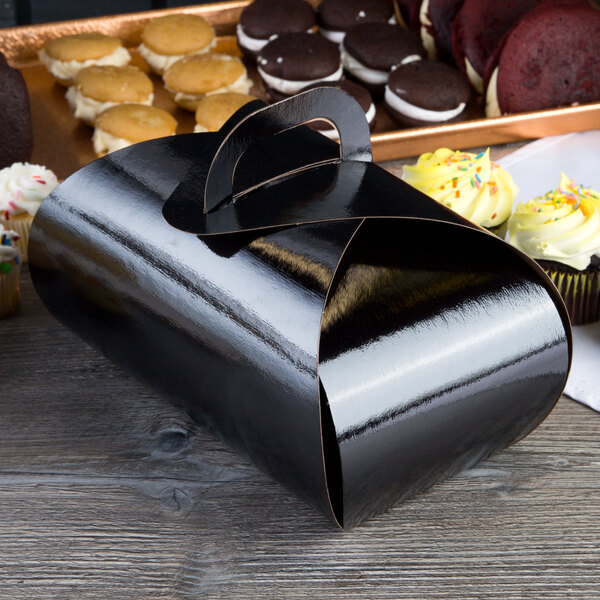 A black Enjay double cupcake tulip box on a table with cupcakes in it.