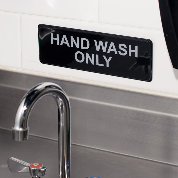 A black and white Thunder Group hand wash only sign on a wall.