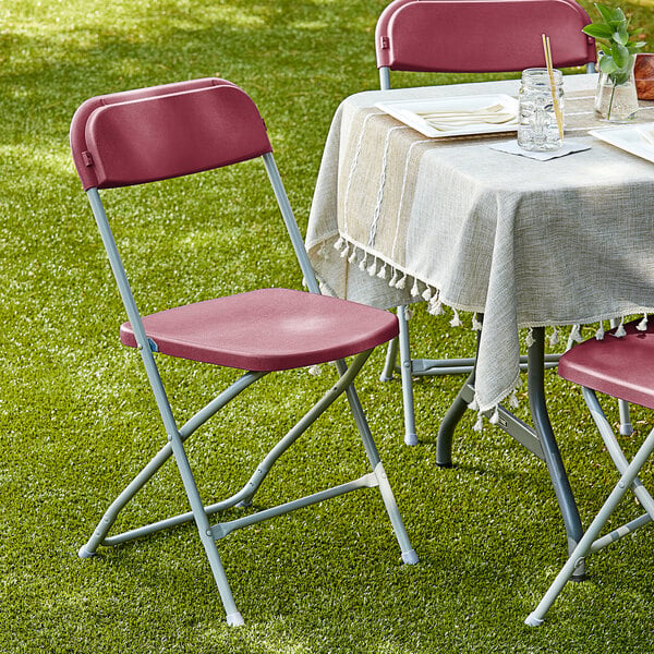 A Lancaster Table & Seating red folding chair on grass.