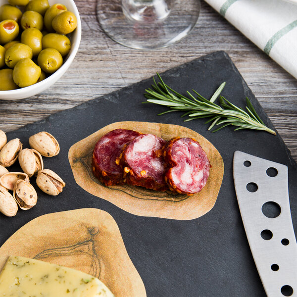 A slate board with American Metalcraft Olive Wood Cheese Paper covering cheese, olives, nuts, and meat.