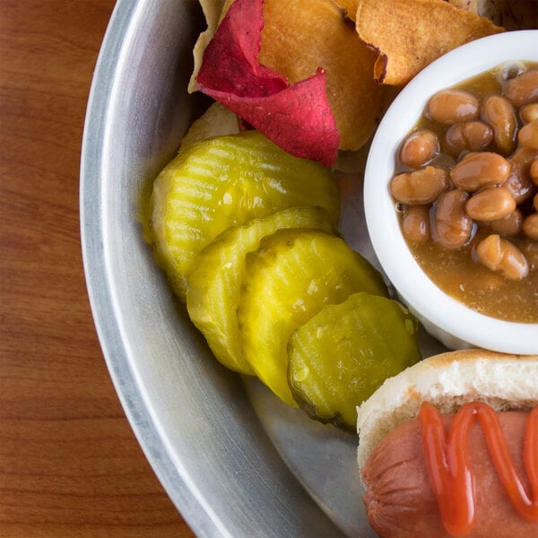 A plate of food with B&G San-Del Kosher Dill pickle chips, hot dogs, and beans.