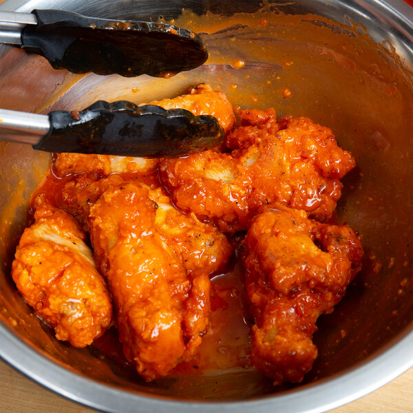 A bowl of chicken wings with Texas Pete Hot Sauce on a school kitchen counter.