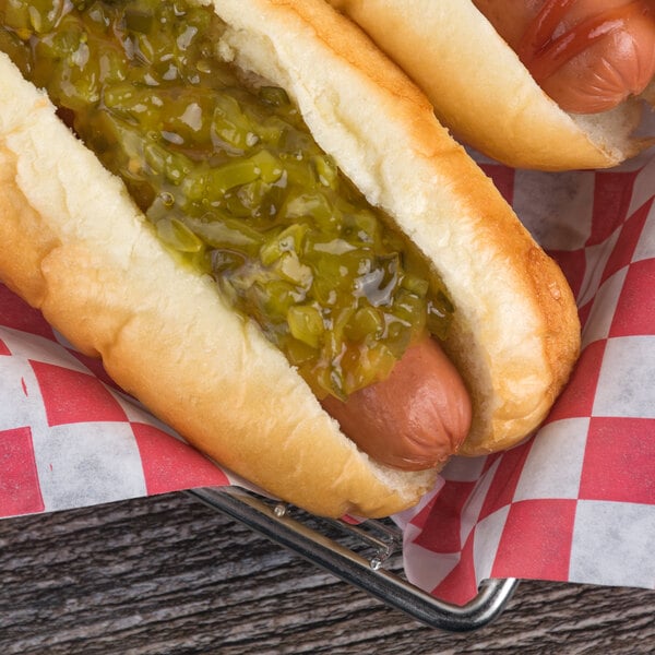 Two hot dogs with B&G sweet relish on a counter in a stadium concession stand.