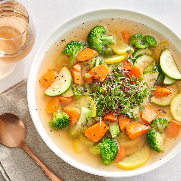 A bowl of Swanson vegetable soup with broccoli, carrots, and other vegetables.