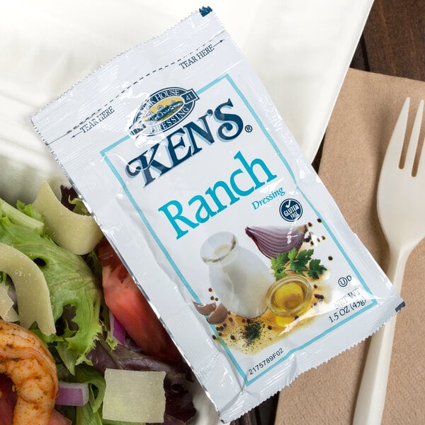 A Ken's Foods ranch dressing packet on a plate of salad.