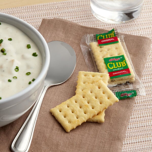 A bowl of soup with a Kellogg's Club cracker.