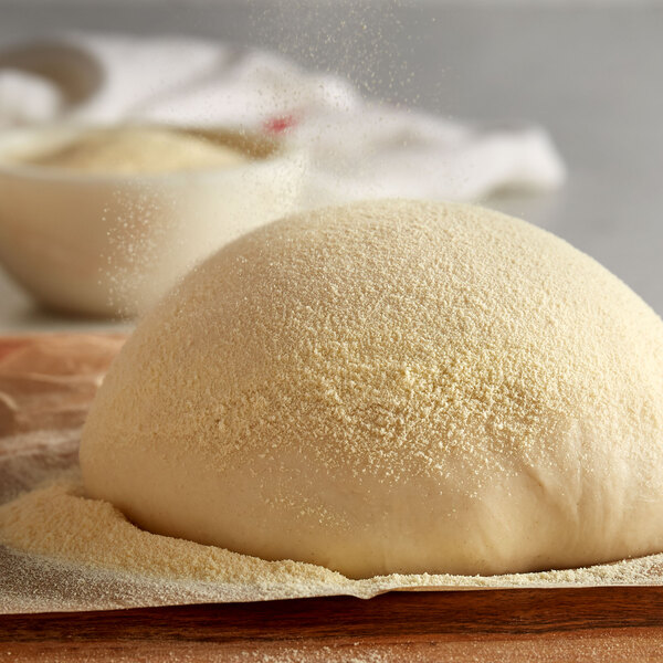 A ball of dough on a wooden surface with Agropur Ingredients Reddi-Sponge powder.