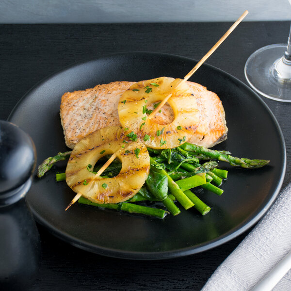 A plate of grilled salmon, asparagus, and pineapple slices on skewers.