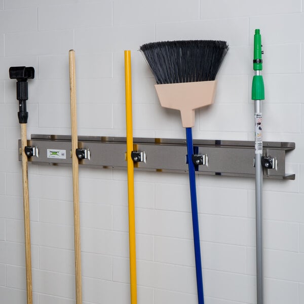 A Regency stainless steel rack holding brooms and mops.
