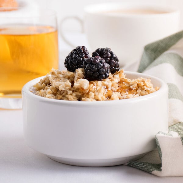 A bowl of regular rolled oats with blackberries and a glass of tea.