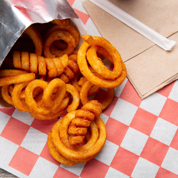 A bag of McCain Redstone Canyon skin-on spiral fries on a table in a fast food restaurant.