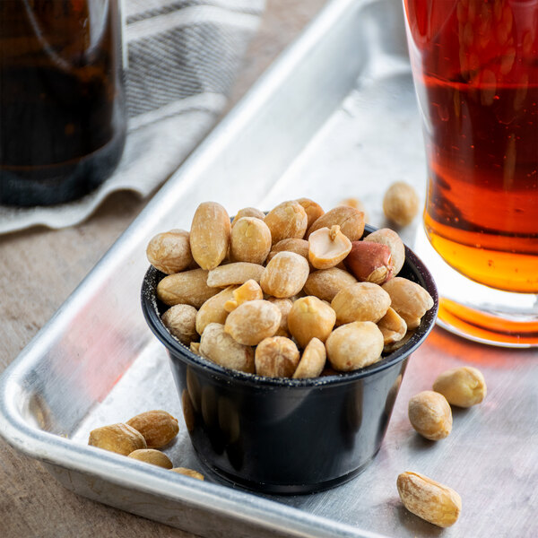 A bowl of Extra Large Roasted Salted Blanched Peanuts on a tray next to a glass of beer.