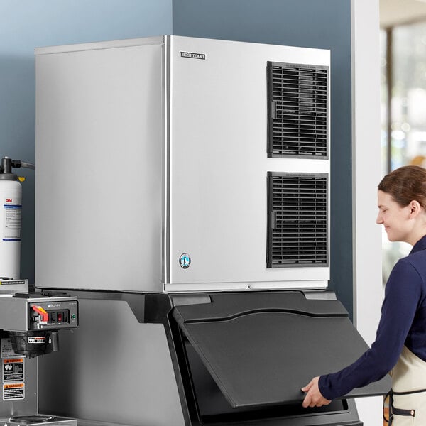 A woman standing next to a large Hoshizaki air cooled ice machine.