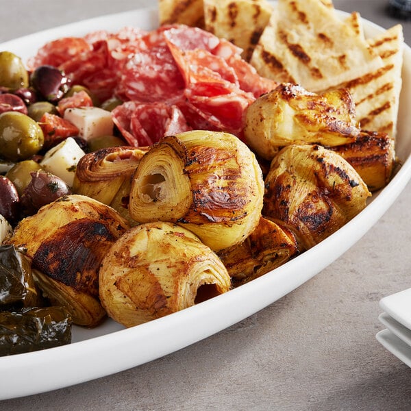 A plate of food with Quartered Artichoke Hearts, cheese, and olives on a table.