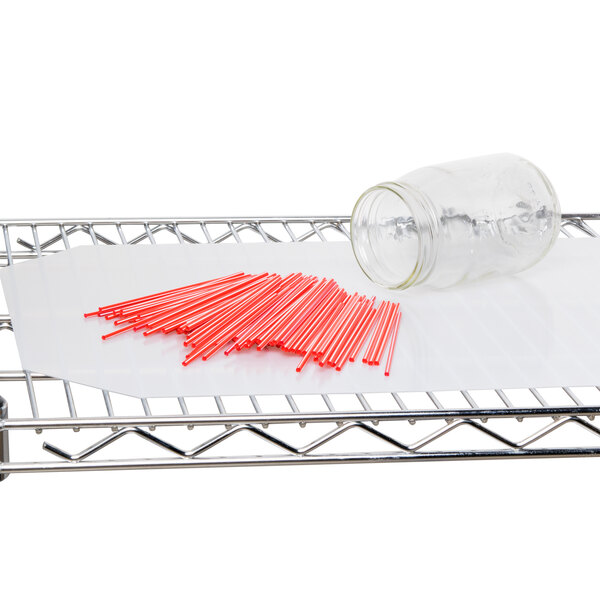 A glass jar of red straws on a Metro metal rack with translucent shelf inlay.