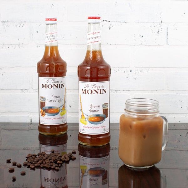A bottle of Monin brown butter flavoring syrup with a white label filled with brown liquid.