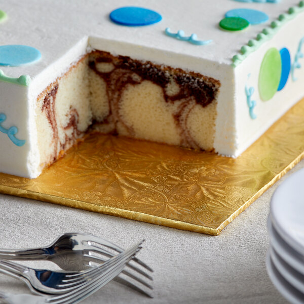 A slice of cake with blue and green icing on a gold Enjay cake board.