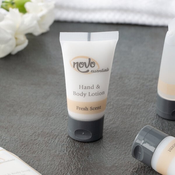 A group of white Novo Essentials hotel and motel body lotion bottles with brown labels on a white surface.
