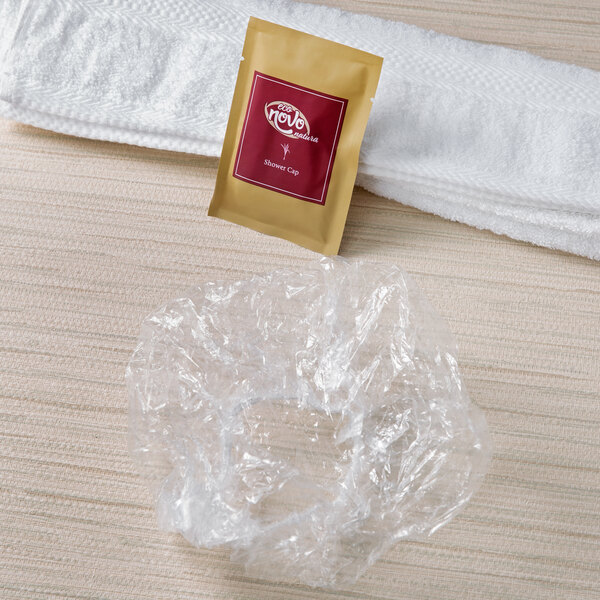 A white towel with a plastic bag of Noble Eco Novo Natura hotel shower caps.