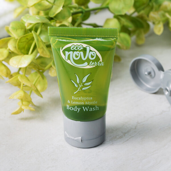 A green bottle of Noble Eco Novo Terra hotel body wash with a flip-top cap next to a plant.