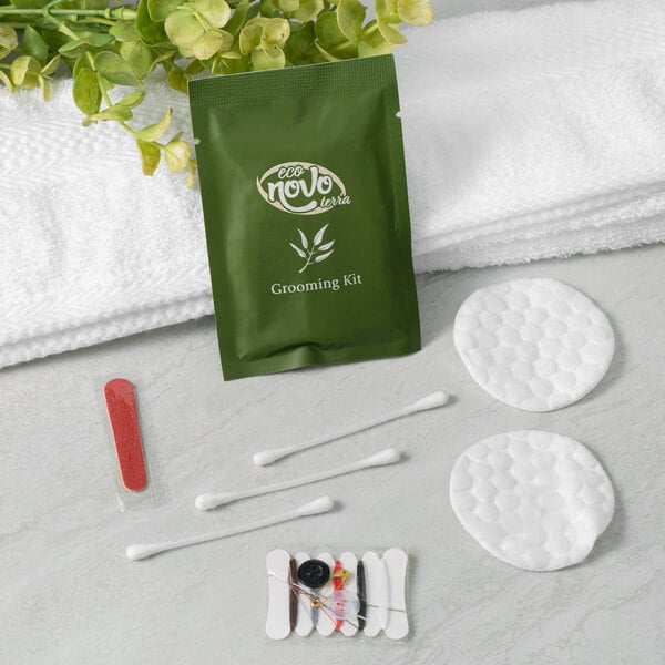 A green Noble Eco Novo Terra grooming kit bag with white text next to cotton pads, cotton balls, and towels.