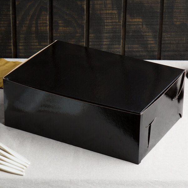 A black Enjay bakery box with a white lid on a white table.