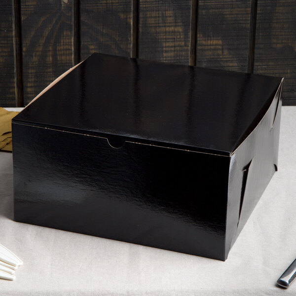 A black Enjay cake box with a lid on a table.