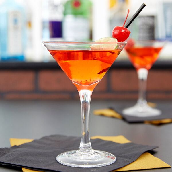 Two Anchor Hocking Ashbury martini glasses with red drinks and cherries on a table.
