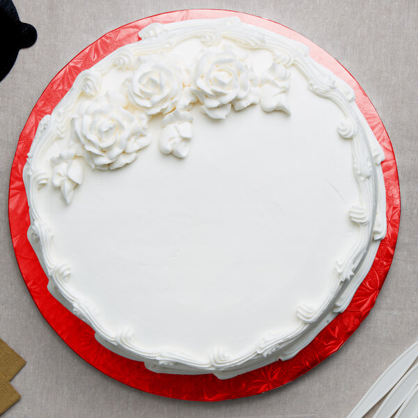 A white cake with white frosting on a red Enjay round cake drum.