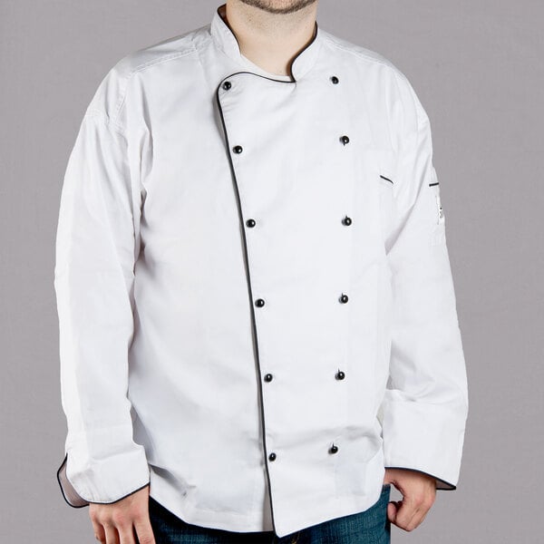 A man wearing a Chef Revival white chef coat with black piping.