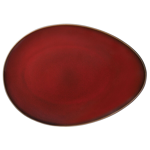 An oval white porcelain plate with a red rim and gold border.