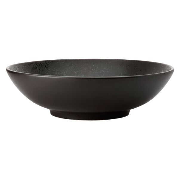 A close-up of a black Oneida Lava porcelain pedestal bowl with speckled specks.