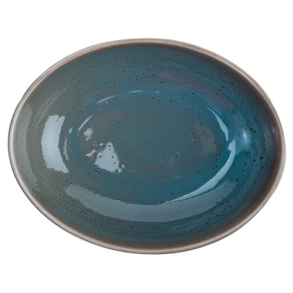 An oval white porcelain bowl with a blue and brown speckled design.
