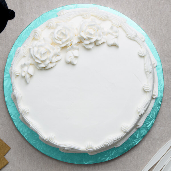 A white cake with white frosting and flowers on a blue Enjay round cake drum.