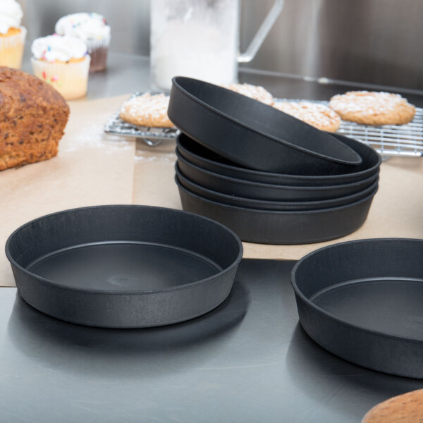 A stack of black Matfer Bourgeat tart/cake pans on a table.