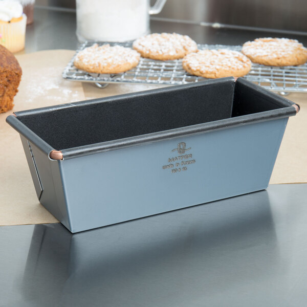 A Matfer Bourgeat flared metal loaf pan with bread and cookies in it.
