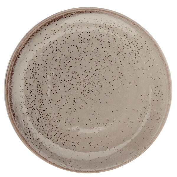 A close up of a white porcelain Oneida Terra Verde Natural coupe plate with speckled dots.
