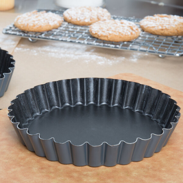 A black metal Matfer Bourgeat fluted tart pan on a white counter.