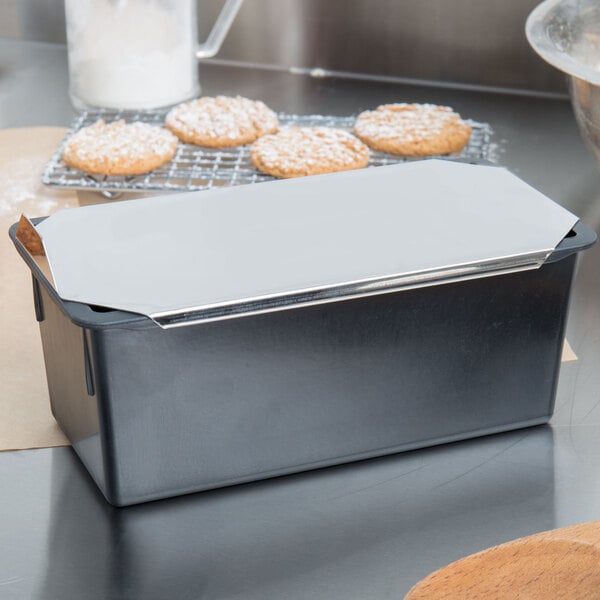 A Matfer Bourgeat non-stick metal loaf pan with a lid on a metal surface with cookies inside.