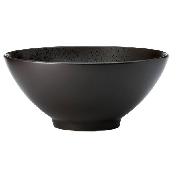 A black porcelain pedestal bowl with specks on a white background.
