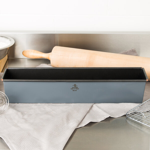 A Matfer Bourgeat non-stick steel bread loaf pan on a counter next to a rolling pin.