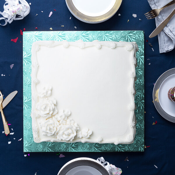 A close up of a white cake on a blue Enjay square cake drum.