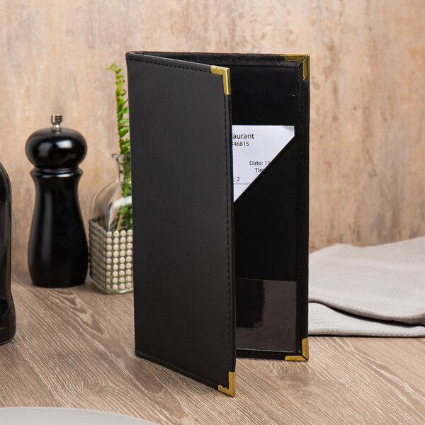 A black leather Menu Solution waiter pad on a table.