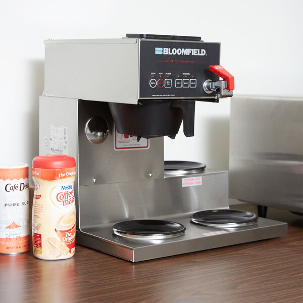 A Bloomfield automatic coffee brewer on a counter next to a can of coffee.