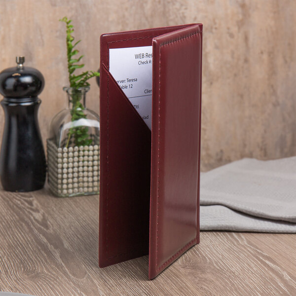 A burgundy Menu Solutions guest check presenter with a piece of paper inside.