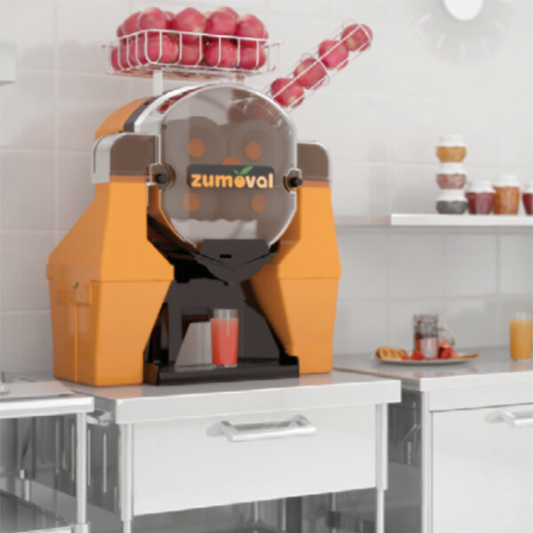 A Zumoval Big Basic manual feed large fruit juice machine with apples on top.