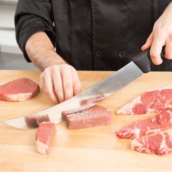 A person using a Victorinox Cimeter Knife to cut meat on a wooden surface.